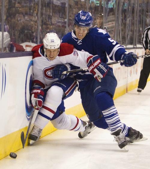 Toronto Maple Leafs' Jake Gardiner (R) checks Montreal Canadiens' Travis Moen along the boards as he reaches for the puck in the first period of their NHL hockey game in Toronto April 13, 2013.  REUTERS/Fred Thornhill (CANADA - Tags: SPORT ICE HOCKEY) - RTXYKS9