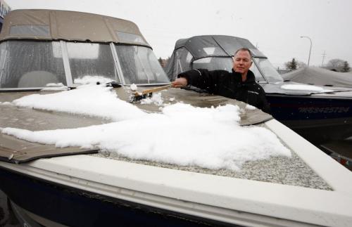 Season Product sales effected by the lingering  winter Äì Jeff Snowdon of Rond's Marine  pushes  snow of  motor  boat . Biz story by Murray McNeill,-  Regent Ave Canadian Tire general Mgr.  Rob Petkau  with season merchandise  ready to move when the weather warms up . KEN GIGLIOTTI / April . 15 2013 / WINNIPEG FREE PRESS
