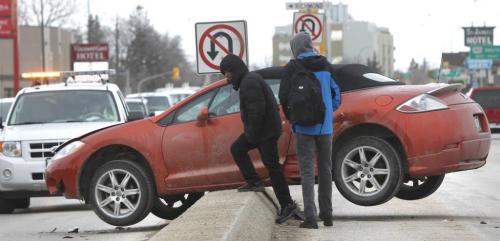 Occupants wait for a tow after their car ended up some how hanging on the traffic median on Portage Ave. in front of Polo Park Tuesday morning. Wayne Glowacki/ Winnipeg Free Press April 16 2013 (WAYNE GLOWACKI/WINNIPEG FREE PRESS) Winnipeg Free Press April 16 2013