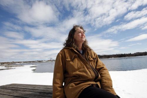 Ingrid Bauer  sits on the banks of the picturesque Winnipeg River  and new dam  construction behind her .She started a petion to save the town pol and grocery store. Manitoba Hydro is building a new spillway  and the old company town in closing . People living in company housing have been given notice to leave .  Pointe du Bois 's  75mw plant  is  located on the Winnipeg River  160km NW of Winnipeg  ,generating 599million kWh  from a 14m drop built in 1909  at a cost of $3.5million. It was built with  16 turbine generators ,the first coming into service in 1911 opening .Bill Redekop story