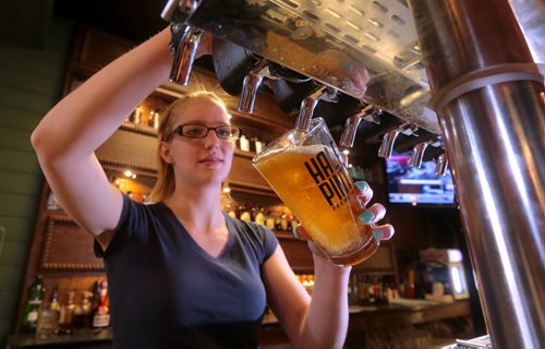 Brandon Sun Waitress Jessica O'Connell pours a pint of beer at The Dock on Wednesday afternoon. Under the provincial budget, minimum wages and taxes on alcohol will both increase putting the squeeze on restaurant owners. FOR LINDSEY (Bruce Bumstead/Brandon Sun)