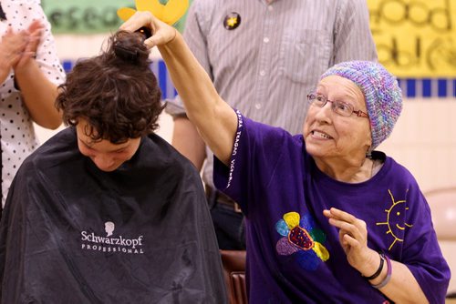 Brandon Sun 19042013 Elizabeth Grant shaves the first strip of hair off of Michael Wenham, 14, during an assembly at King George School on Friday. Wenham raised $8414 for the Canadian Cancer Society in Grant's honour in advance of the event. Grant has been battling mantle cell lymphoma since January. (Tim Smith/Brandon Sun)