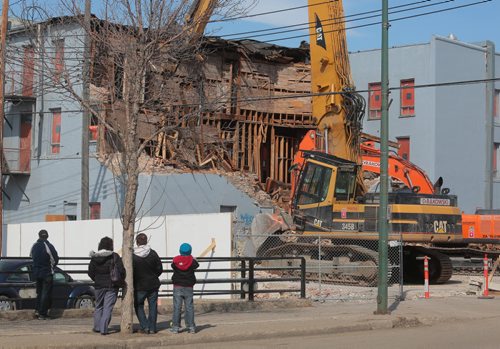 Brandon Sun Bystanders watch as large excavating machines tear down the walls of the Brandon Inn at the corner of Ninth Street and Princess Avenue on Thursday evening. (Bruce Bumstead/Brandon Sun)