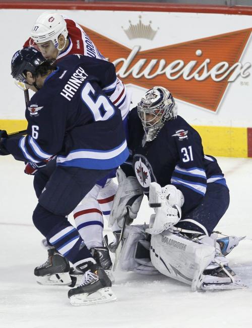 Winnipeg Jets' goaltender Ondrej Pavelec (31) tips the puck as Jet Ron Hainsey (6) and Montreal Canadien Rene Bourque (17) fight for the rebound during first period NHL action in Winnipeg on Thursday, April 25, 2013. THE CANADIAN PRESS/John Woods