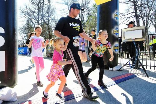 Brad Sanford Is escorted across the finish line by his daughters (l-r) Randi, 8, Karsyn, 4, and Alex, 6, during the Winnipeg Police Service half marathon at Assiniboine Park Sunday.  130505 May 05, 2013 Mike Deal / Winnipeg Free Press