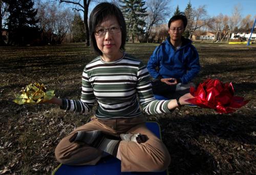 Maria Cheung meditates holding "Lotus Flowers" Monday evening. HuaiDong Wang behind her. See Brenda Suderman's story re: Falun Gong celebrate 21st anniversary May 6, 2013 - (Phil Hossack / Winnipeg Free Press)