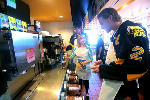 Brandon Sun Star FM's Carly Frey works behind the counter with Brandon Wheat Kings' Eric Roy and captain Ryan Pulock, right, during Wednesday's McHappy Days, in support of Westman Dreams for Kids, at the Richmond Avenue McDonald's restaurant. (Bruce Bumstead/Brandon Sun)