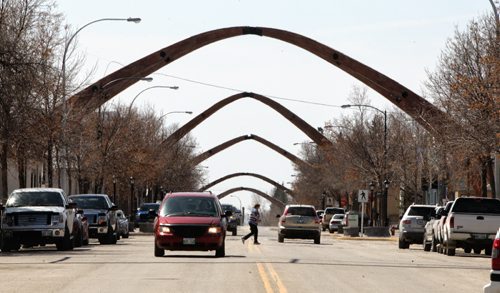 Crossing Main Street in downtown Russell, Manitoba, a pedestrian is dwarfed by the large wooden arches that were rescued from an arena demolition in Dauphin, Manitoba. The wooden rafters were originally built by a business in Russell and were given a new life in 2007 when they were diverted from a landfill to give the town a unique skyline.  130508 May 08, 2013 Mike Deal / Winnipeg Free Press