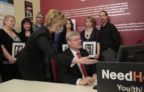Prime Minister Stephen Harper at a computer with Signy Arnason, Director of Cybertip.ca surrounded by family of victims of cyberbulling at media photo op at the Canadian Centre For Child Protection Friday. Wayne Glowacki/Winnipeg Free Press May 10 2013