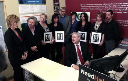 Prime Minister Stephen Harper at a computer speaks with Signy Arnason, Director of Cybertip.ca with from (ltoR) Joyce Bateman,MP,  and  family of victims of cyberbulling Pam Murchison holds a portrait of Jenna Bowers-Bryanton, Carol Todd with portrait of Amanda Todd, Glenford Canning, Krista Canning, Jo-Anne Landolt wiyth portrait of Kimberly Proctor, Leah-Jane Parsons with a potrait of Rehtaeh Parsons and Jason Barnes at media photo op at the Canadian Centre For Child Protection Friday. Wayne Glowacki/Winnipeg Free Press May 10 2013