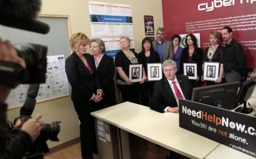Prime Minister Stephen Harper at a computer with (ltor) Signy Arnason, Director of Cybertip.ca,  Joyce Bateman,MP,  and  family of victims of cyberbulling Pam Murchison holds a portrait of Jenna Bowers-Bryanton, Carol Todd with portrait of Amanda Todd, Glenford Canning, Krista Canning, Jo-Anne Landolt with a portrait of Kimberly Proctor, Leah-Jane Parsons with a portrait of Rehtaeh Parsons and Jason Barnes at media photo op at the Canadian Centre For Child Protection Friday. Wayne Glowacki/Winnipeg Free Press May 10 2013
