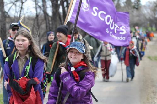 Brownies and Scouts walk together holding flags as they make thier way into Assiniboine Park with a large group of scouts for the a National Scout day. . A 16 km hike with flags, youths between the ages of 5 to 26 and their leaders, in full uniform. Jamboree On The Trail (JOTT) is a first for Winnipeg but the 16th in Canada. Standup photo  May 11 2013,  Ruth Bonneville Winnipeg Free Press