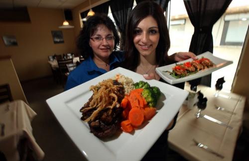 Roula Alevizos (left) and her daughter Elleni hold a "Blackened" Ribeye diner and "Gator bites", two of the menu options at "The Woods Bistro in Charleswood. May 17, 2013 - (Phil Hossack / Winipeg Free Press)
