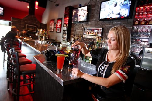 Brandon Sun 17052013 Ruth Jaster, a server with Joe Beeverz Bar & Grill, pours a glass of wine at the local watering hole and restaurant on Friday afternoon.  (Tim Smith/Brandon Sun) For Charles Tweed story***