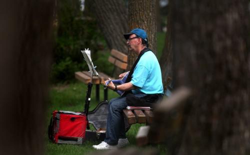 Larry Eby managed to find just the right sunny spot  in Assiniboine Park Monday evening. The retired custodian is a regular busker at City Place and took advantage of Monday's brief evening encounter with the sun to practice his fretwork. May 27, 2013 - (Phil Hossack / Winnipeg Free Press)