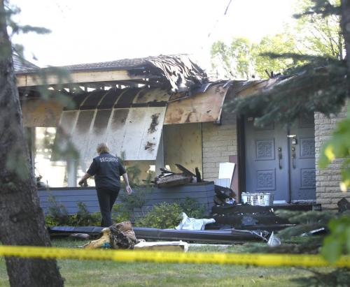 A security member Thursday morning at the scene of a house fire on Foxdale Ave. at Delbrook Cres. that started Wednesday and caused a reported $1 million in damage.      (WAYNE GLOWACKI/WINNIPEG FREE PRESS) Winnipeg Free Press June 6 2013