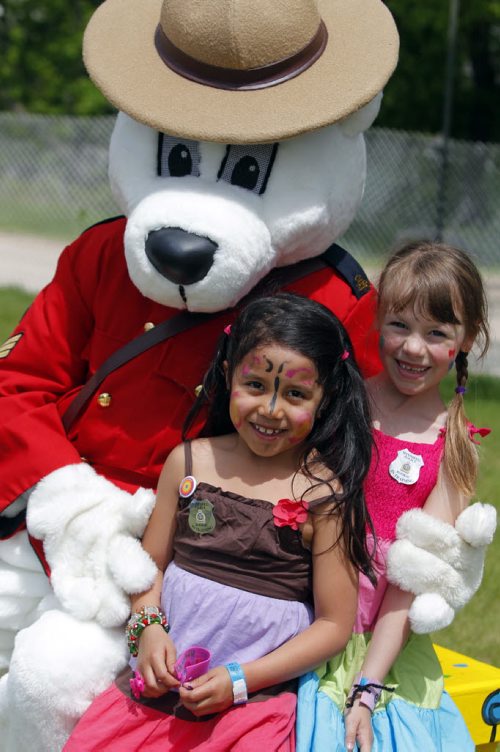 Kidsfest at the Forks. Malaya Fernandes and Sofia Morgan pose for a photo with the RCMP mascot on site. June 6, 2013  BORIS MINKEVICH / WINNIPEG FREE PRESS
