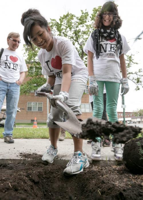 Students from Champlain School planted a butterfly garden outside the North Winds property management offices at Main St and Anderson Ave on Monday. Grade 6 student Faith Cruz digs to plant a small shrub and Netasha Cutlip watches.  130610 - Monday, June 10, 2013 - (Melissa Tait / Winnipeg Free Press)