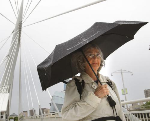 Louise Pallett walks over the Esplanade Riel to work on a rainy Friday morning. Weather story(WAYNE GLOWACKI/WINNIPEG FREE PRESS) Winnipeg Free Press June 14 2013
