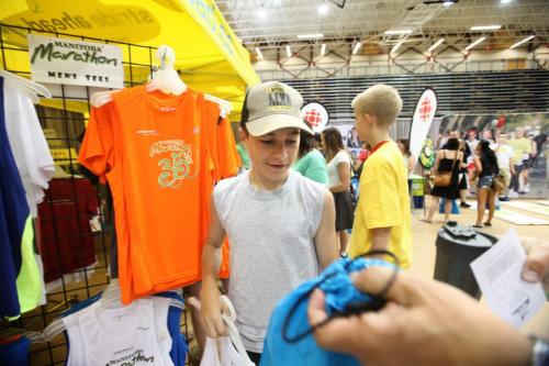 Fifteen year old AJ Toews looks at buying a new running shirt to wear at the marathon on Sunday morning. when he competes in his 2nd half Manitoba Marathon.  The Manitoba Marathon 2 day Expo is on until 5pm Saturday and features last minuite registration and bid number pickup for all marathoners competing in Sunday's race. Standup photo..  Photography by Ruth Bonneville Winnipeg Free Press June 15,, 2013