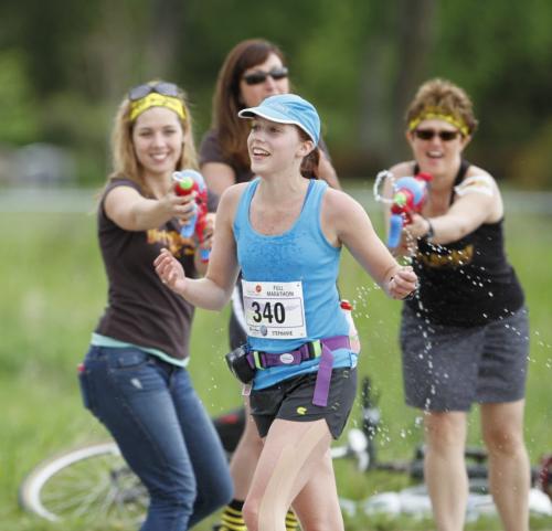 Spectators spray a runner with water guns at Mile 24 of the Manitoba Marathon in Winnipeg on Sunday, June 16, 2013. (JESSICA BURTNICK/WINNIPEG FREE PRESS)