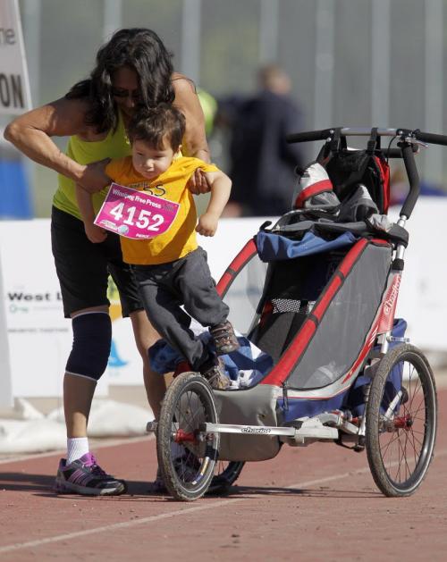 A 10K participant takes her child from his stroller to walk across finish line at the University of Manitoba during the 35th Annual Manitoba Marathon, Sunday, June 16, 2013. (TREVOR HAGAN/WINNIPEG FREE PRESS)
