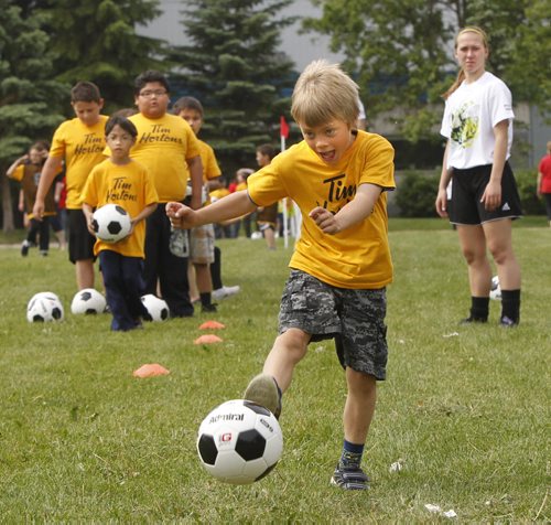 Nicholas Laurie,6, a student at Brooklands School  goes through a soccer drill with guidance from youth volunteer mentor Adrianna Karpa after a provincial announcement Thursday a new Mobile Mini Soccer Program will be offered for inner-city children. The program offered weekly at four sites by volunteer youth mentors from the five competitive soccer districts in Winnipeg.   see release.(WAYNE GLOWACKI/WINNIPEG FREE PRESS) Winnipeg Free Press June 20 2013