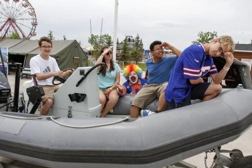 The Canadian Forces display at the Red River Exhibition attracted a number of young people on Thursday, June 20, 2013. (left to right) Martin Rickey, Diana Lisney, Kim Laberinto and Lucas Hrynyk spotted the display from atop the ferris wheel and decided to check things out from one of the military's rigid hulled inflatable boats (also known as an RHIB). According to naval Chief Joanne Legge, the display is intended as an educational tool moreso than a recruiting effort. (ELIZABETH FRASER) (JESSICA BURTNICK/WINNIPEG FREE PRESS)