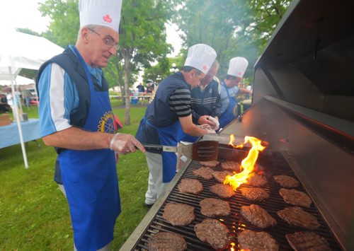 Brandon Sun Peter Kowalchuk of the Brandon Rotary Club flips burgers on the grill during Thursday's annual Burger Day charity barbecue held in Princess Park. (Bruce Bumstead/Brandon Sun)