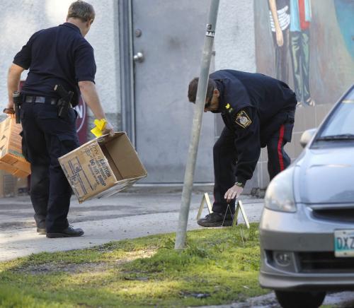 Winnipeg Police officer places an evidence marker on the sidewalk on Wolseley Ave. between Sherbrook St. and Furby St. Monday after  an early morning shooting.Adam Wazny story (WAYNE GLOWACKI/WINNIPEG FREE PRESS) Winnipeg Free Press June 24 2013