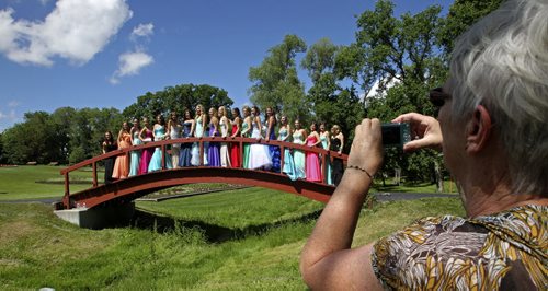 Kathleen Wright takes a photo of her granddaughter who is amongst a group of girls graduating from West Kildonan Collegiate posing on the footbridge at Kildonan Park Wednesday afternoon. 130626 - Wednesday, June 26, 2013 -  (MIKE DEAL / WINNIPEG FREE PRESS)