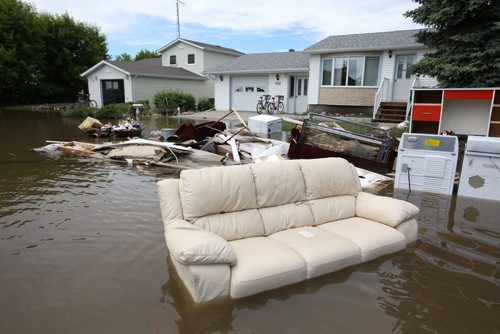 Brandon Sun 26062013 Furniture and appliances sit in flood water surrounding a home in the community of Reston on Wednesday after another powerful storm flooded several streets in the community again on Tuesday evening. (Tim Smith/Brandon Sun)
