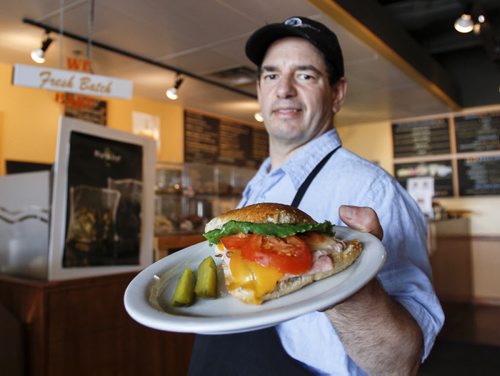 Daily Grind owner Tom Paquette shows off the baked ham/roast turkey and cheese sandwich at 3393 Portage Ave. Friday, June 28, 2013. (JESSICA BURTNICK/WINNIPEG FREE PRESS)