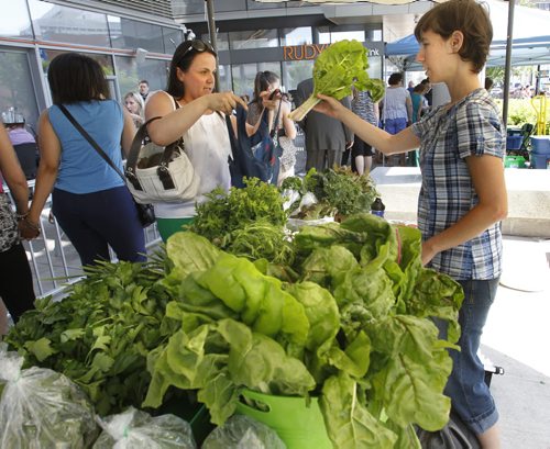 At left, Gabriela Klimes purchases chard from Stephanie Steele at one of the twenty vendors set up Thursday for the first day of the  Downtown Winnipeg Farmers' Market in the Manitoba Hydro Place Plaza at the corner of Graham Ave. and Edmonton St.  Items for sale include, baked goods, art work, clothing, bison, rainbow trout,chicken and lamb. The weekly market is on Thursdays and runs till Sept. 5 at 11:30A.M.-5:30P.M.  Wayne Glowacki/Winnipeg Free Press July 4 2013