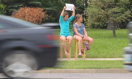 Brandon Sun LOOKING FOR BUSINESS -- Randy Burnett and Delaney Werniski try to attract attention from passing motorist on First Street to stop at their face painting booth on Queens Avenue on Friday afternoon. (Bruce Bumstead/Brandon Sun)