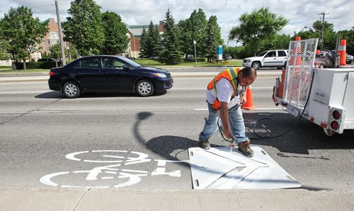 Crews from the city are out Sunday morning painting bicycle path signs on roads in the Charleswood area. 130707 July 07, 2013 Mike Deal / Winnipeg Free Press