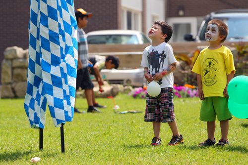 Brandon Sun 06072013 Two young boys gaze up at Stilt walker Isaac Girardin during the second day of the Brandon Multicultural Summer Festival at Princess Park on Saturday. (Tim Smith/Brandon Sun)