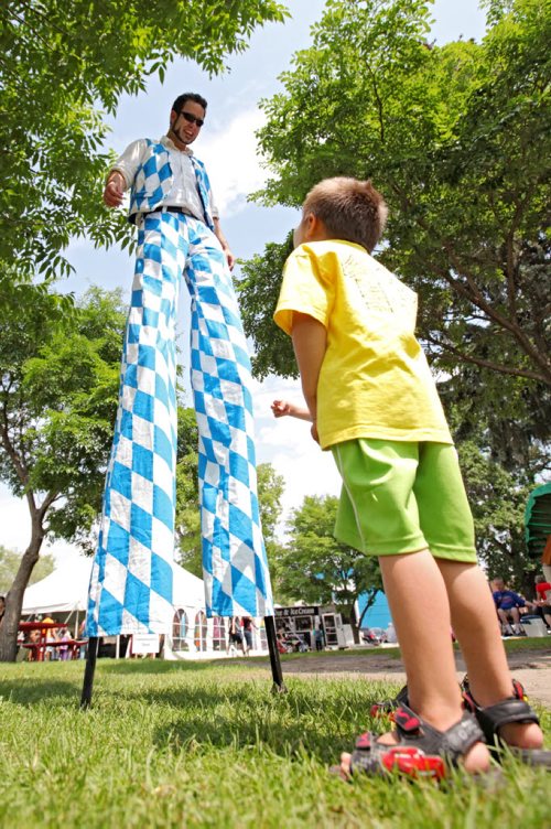 Brandon Sun 06072013 A young boy gazes up at Stilt walker Isaac Girardin during the second day of the Brandon Multicultural Summer Festival at Princess Park on Saturday. (Tim Smith/Brandon Sun)