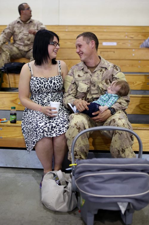 Brandon Sun 08072013 Corporal Dan Gardiner visits with his wife Callie and their son Bohdan in the Multi-Purpose Training Facility at CFB Shilo on Monday morning prior to deploying to Kabul as part of the final rotation of Canadian soldiers serving in Afghanistan. Gardiner's deployment, his first to Afghanistan, will be approximately four month's.  (Tim Smith/Brandon Sun)