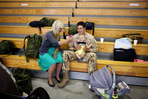 Brandon Sun 08072013 Mandy Burton takes a photograph of her husband Corporal Connor Burton and their son Avery in the Multi-Purpose Training Facility at CFB Shilo on Monday morning prior to Burton deploying to Kabul as part of the final rotation of Canadian soldiers serving in Afghanistan.   (Tim Smith/Brandon Sun)