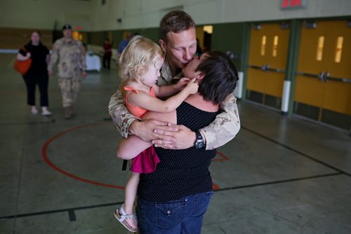 Brandon Sun 08072013 Corporal Krister Pohjolainen kisses his wife Natalie goodbye and hugs their two-year-old daughter Elise in the Multi-Purpose Training Facility at CFB Shilo on Monday morning prior to deploying to Kabul as part of the final rotation of Canadian soldiers serving in Afghanistan. Pohjolainen's deployment, his first to Afghanistan, will be approximately four month's.  (Tim Smith/Brandon Sun)