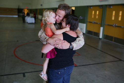 Brandon Sun 08072013 Corporal Krister Pohjolainen hugs his wife Natalie goodbye and kisses their two-year-old daughter Elise in the Multi-Purpose Training Facility at CFB Shilo on Monday morning prior to deploying to Kabul as part of the final rotation of Canadian soldiers serving in Afghanistan. Pohjolainen's deployment, his first to Afghanistan, will be approximately four month's.  (Tim Smith/Brandon Sun)