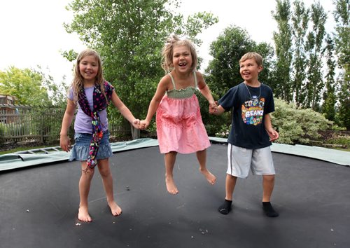 Sophia (in dress, centre)  plays with her brothe Ryland-9yrs  and sister Alexis 7yrs  on their trampoline outside their home in Landmark Manitoba. 

  The close knit family are happy with the care Sophia received from the children's hospital after she was diagnosed with cancer when she was 2 and a half years old. 
  See Geoff Kirbyson's story.     July 13, , 2013,  Ruth  Bonneville ,Winnipeg Free Press