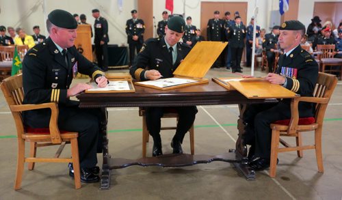 Brandon Sun Incoming Base Commander Lt-Col. Stephen Joudrey, left, signs the command papers with Col. Derek Macaulay, Commander 1 Area Support Group, and outgoing Base Commander Lt-Col. Richard Goodyear, right, during Tuesday's Change of Command Ceremony at CFB Shilo. Lt-Col. Jourdey is returning to Shilo having served as Deputy Base Commander and Chief of Staff as well as Deputy Commanding Officer with 2PPCLI. (Bruce Bumstead/Brandon Sun)