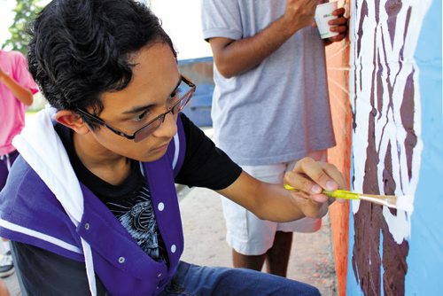 Canstar Community News July 4, 2013 -- Kiou Villaymayor, 16, works on a portion of a mural going up on the side of 7-Eleven at Mountain Avenue and McPhillips Street on July 4. The mural, sponsored by Take Pride Winnipeg, involved 25 students from the Wayfinders program in the Seven Oaks School Division. (MATT PREPROST/CANSTAR NEWS)