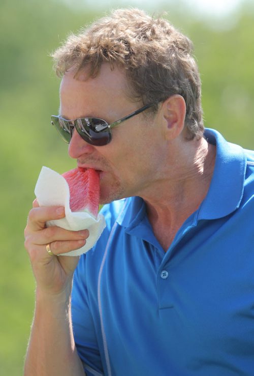 Brandon Sun Brian Deutscher cools off with a watermelon slice on the seventeenth tee off during Thursday's Westman Dreams for Kids charity golf tournament at the Shilo Golf Course. (Bruce Bumstead/Brandon Sun)