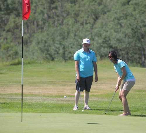Brandon Sun Nycolle Adams of J&G Homes, chips onto a green as Rodney Harvey looks on during Thursday's Westman Dreams for Kids charity golf tournament held at the Shilo Golf Course. (Bruce Bumstead/Brandon Sun)
