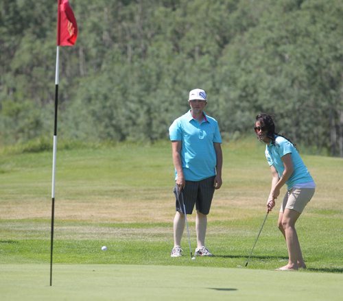Brandon Sun Nycolle Adams of J&G Homes, chips onto a green as Rodney Harvey looks on during Thursday's Westman Dreams for Kids charity golf tournament held at the Shilo Golf Course. (Bruce Bumstead/Brandon Sun)