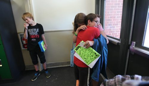Noah (in red) give Mackenzie a hug  while Avery looks on just before leaving  Windsor School for the last time.  Grade 8 Windsor School students spend the final moments on the last day of school writing in each others yearbooks, cleaning out lockers and sharing tearful goodbyes as they transition from grade school to High School in the fall of this year.  Some of the students have been attending Windsor School  with the same group of friends since kindergarden. Although most of the students will be going to Glenlawn Collegiate some have plans to attend a different high school.  Noah holds his year book packed full of messages from his classmates in his arm in the hallway at Windsor School before leaving the school for the final time.  Photo's taken on June 28, 2013 Class of 2017 Doug Speirs story.  July 11 , 2013 Ruth  Bonneville , Winnipeg Free Press