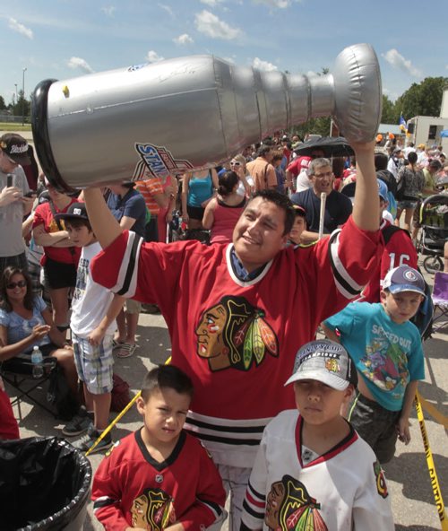 Chris Guimond hoists his inflatable Stanley Cup replica as he and his sons at left Sabastien,6, and Felix, 9, came from Sagkeeng First Nation to see Chicago Blackhawks captain Jonathan Toews and the real cup at the Jonathan Toews Community Centre Friday afternoon. Randy Turner story Wayne Glowacki/Winnipeg Free Press July 19 2013